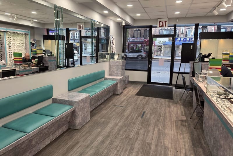 The front of the practice: teal upholstered bench seating along one wall, the reception desk behind a glass partition, and storefront windows onto Brighton Beach Avenue.